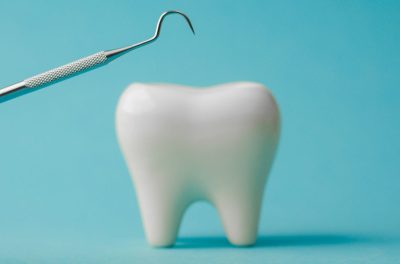 dental-probe-near-white-tooth-model-on-plain-blue-2025-12-07-02-20-06-utc